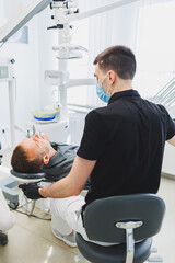 Fototapeta premium Dental office, examining a patient in a dental chair. Dental treatment is performed by a doctor and an assistant. Dental care.