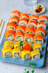 Sushi rolls set with salmon, shrimp and mango on light blue background, Japanese cuisine