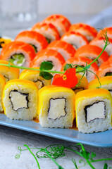 Sushi rolls set with salmon, shrimp and mango on light blue background, Japanese cuisine
