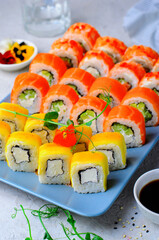 Sushi rolls set with salmon, shrimp and mango on light blue background, Japanese cuisine