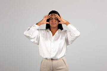 Sad young african american business woman presses her hands to head suffering from pressure, stress and headache