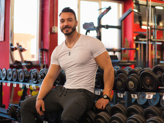 Fototapeta na wymiar Muscular, shirtless male bodybuilder resting in gym during workout