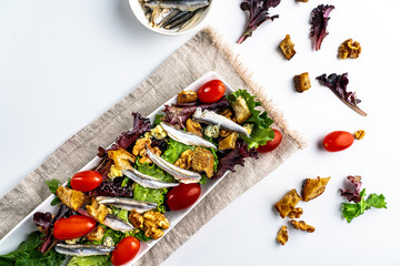 Salad featuring white Spanish anchovies on a bed of mixed greens with grape tomatoes, blue cheese, sourdough croutons, and walnuts.