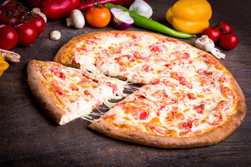 Pizza tradicional italiana com muito queijo tomate em cima da mesa de madeira com legumes