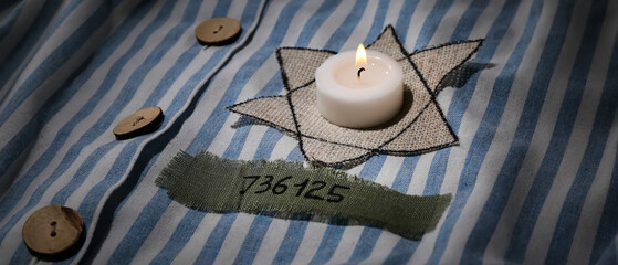 David star and burning candle on prisoner robe. International Holocaust Remembrance Day - obrazy, fototapety, plakaty