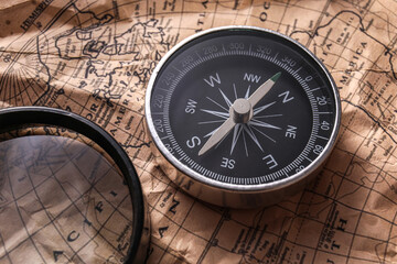 Compass and magnifier on world map, closeup