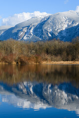 Fototapeta na wymiar Snow covered Washington Cascade moutains reflecting in lake under blue sky