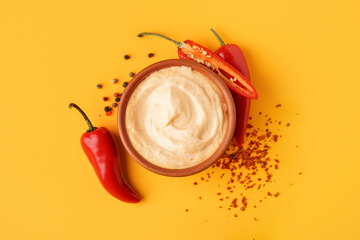 Bowl of tasty chipotle sauce and fresh jalapeno peppers on color background