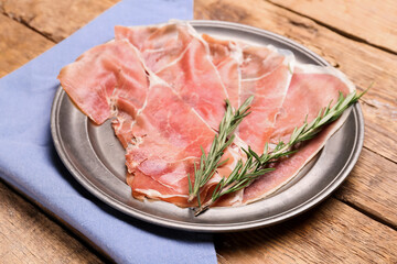 Plate with slices of tasty ham and rosemary on wooden background, closeup