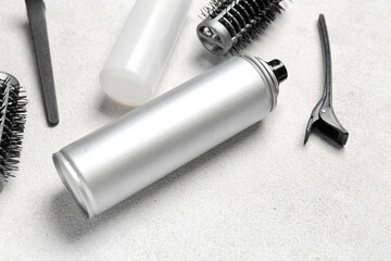 Hair sprays with clips and brushes on light background, closeup