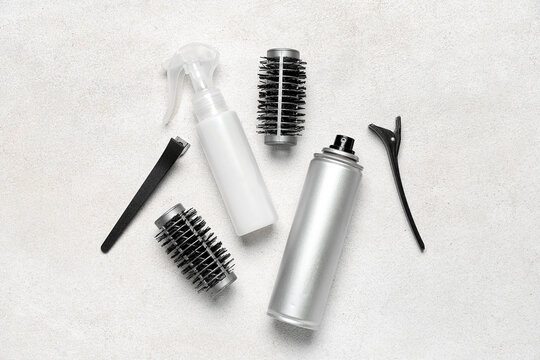 Hair sprays with clips and brushes on light background