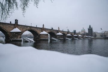 Prague in the snowfall. View of the Charles Bridge and the Vltava River on a winter day. Czechia