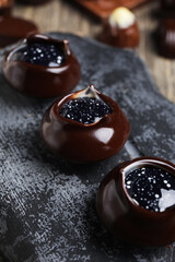 Dark board with chocolate candies on wooden table, closeup