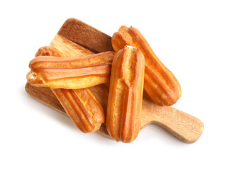 Wooden cutting board with delicious eclairs on white background