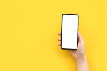 Fototapeta na wymiar Female hand with modern mobile phone on yellow background