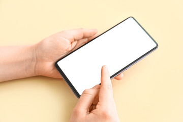 Female hands with modern mobile phone on color background, closeup