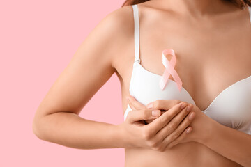 Woman in underwear with pink ribbon on color background, closeup. Breast cancer awareness concept