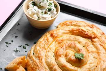 Baking tray with delicious cheese pie on pink background
