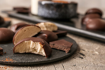 Dark board with sweet chocolate bird's milk candies on grunge background, closeup