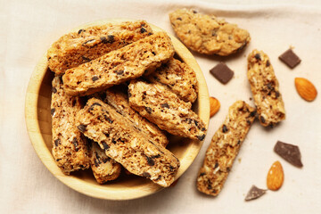 Bowl with tasty biscotti cookies, almond nuts and chocolate on light background