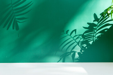Fototapeta na wymiar Minimal modern product display on deep green background with palm leaves shadow overlay