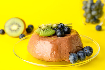 Plate with delicious chocolate pudding, kiwi and blueberry on yellow background