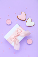 Gift with cookies, candles and hearts on lilac background. Valentine's Day celebration