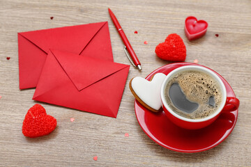 Cup of coffee with cookie, envelopes, candles and hearts on wooden background. Valentine's Day...