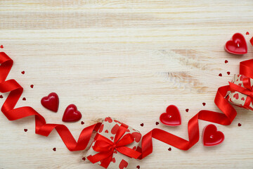 Frame made of gifts, ribbon, candles and hearts on light wooden background. Valentine's Day celebration