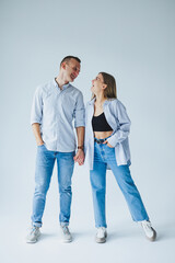 Fototapeta premium Relationship concept - photo of a happy couple in white shirts and jeans on a white background. Happy young couple