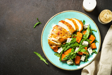 Warm salad with baked chicken breast, pumpkin, blue cheese and arugula. Dash diet, keto diet meal. Top view with copy space.