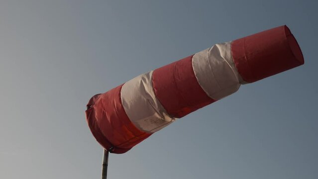 Windsock blowing with blue sky in the background. Slow motion.
