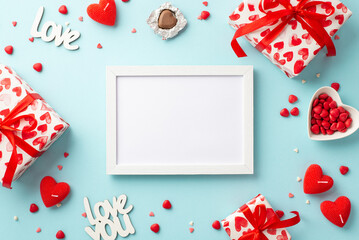 Valentine's Day concept. Top view photo of photo frame present boxes heart shaped candles candies inscriptions love and saucer with sprinkles on isolated pastel blue background with copyspace