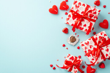 Valentine's Day concept. Top view photo of gift boxes heart shaped candles chocolate candies and sprinkles on isolated pastel blue background with copyspace