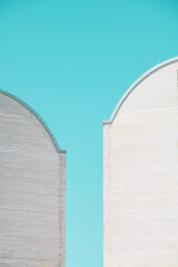 Twin facades of twin white brick buildings with clear blue sky