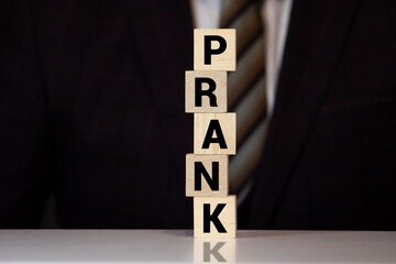 A small piece of paper with the word prank and a smile icon on top of a red ring box and a ring leaning to the side.