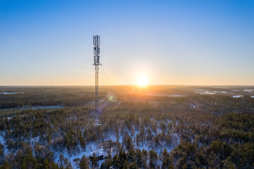 A telecommunications antenna at sunset in a beautiful winter forest landscape. 5G internet mast....