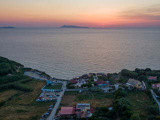Aerial drone photo of beautiful sunset at Loggas beach beach bar on top of high rocky white cliff,  North Corfu island, Ionian, Greece