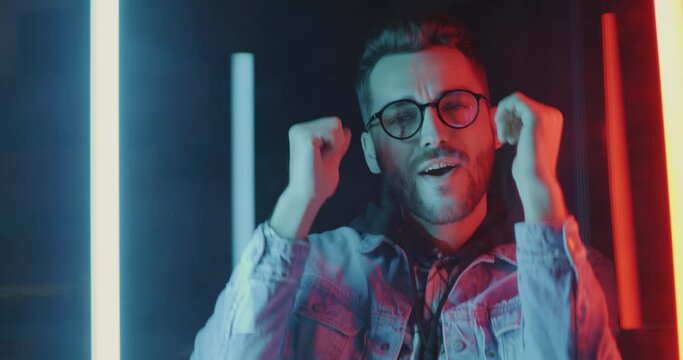 Slow motion of male student partying against multicolor neon background enjoying nightlife alone. People and futuristic effect concept.