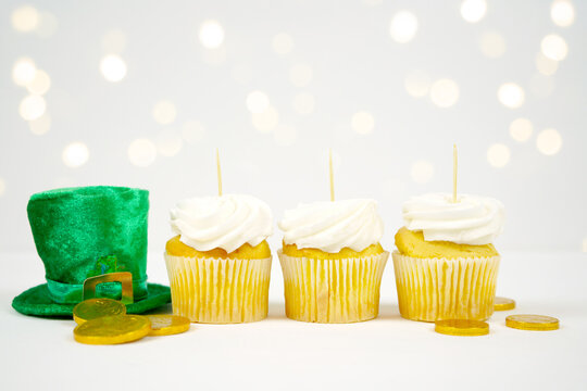 Cupcake cake topper product mockup. St Patrick's Day product mockup. Styled with green leprechaun hat and gold coins against a bokeh party lights background. Negative copy space.