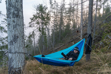 Fototapeta premium Young caucasian male lying and resting in a hammock with camera.