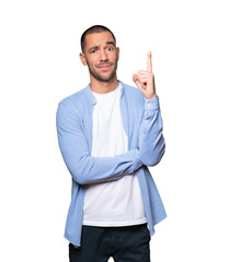 Hesitant young man pointing up with his finger