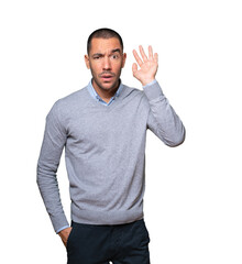 Concentrated young man making a gesture of trying to hear something