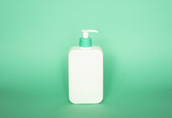 White bottle with a green dispenser for liquid soap, shampoo, gel on green background.