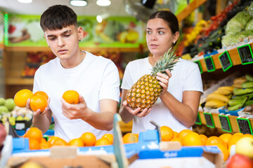 Cheerful young couple choosing fresh fruits in supermarket