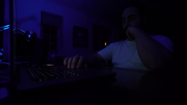 hacker: hacker who writes code. man working on laptop in night light