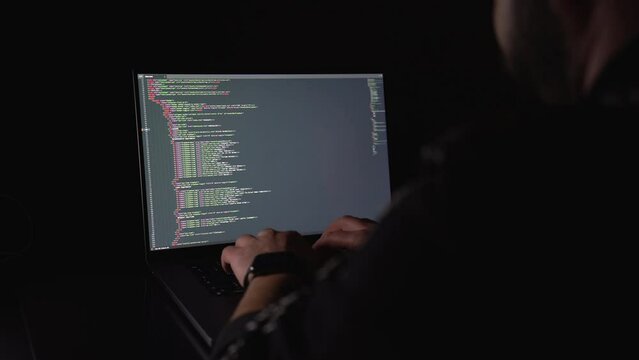 hacker: hacker who writes code. man working on laptop in night light
