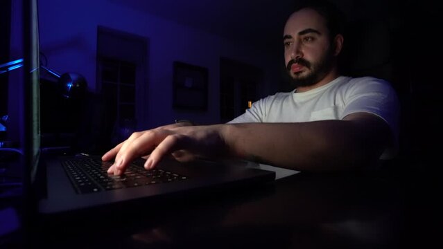 hacker: hacker who writes code. man working on laptop in night light