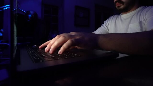 hacker: hacker who writes code. man working on laptop in night light
