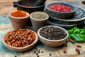 Colorful ground spicy chili peppers , pimento and curcuma is clay pots close up